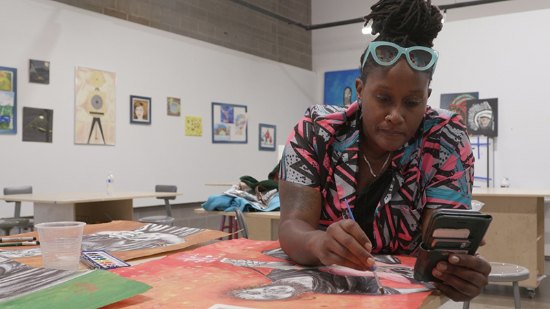Artist Shaunie Berry at work on a colorful painting.